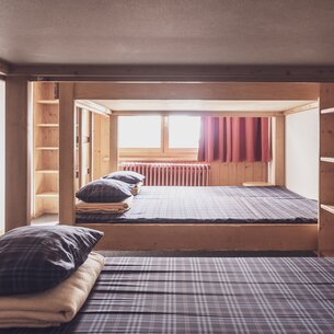 Multi-bed room with double bunk beds and clothes racks  | © Davos Klosters Mountains 