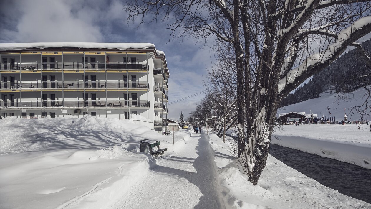 Winterwanderweg entlang des Landwassertal, im Hintergrund ein mehrstöckiges Gebäude | © Davos Klosters Mountains 