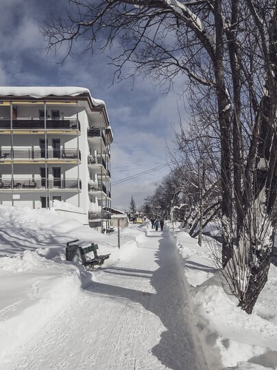 Winterwanderweg entlang des Landwassertal, im Hintergrund ein mehrstöckiges Gebäude | © Davos Klosters Mountains 