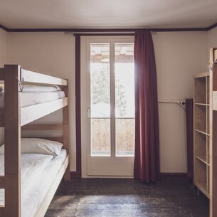 Mehrbettzimmer mit Stockbetten und Kleiderablagen | © Davos Klosters Mountains 