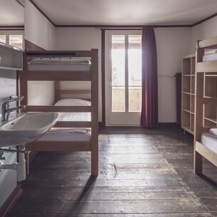Multi-bed room with bunk beds incl. bed linen, washbasin and clothes storage | © Davos Klosters Mountains 
