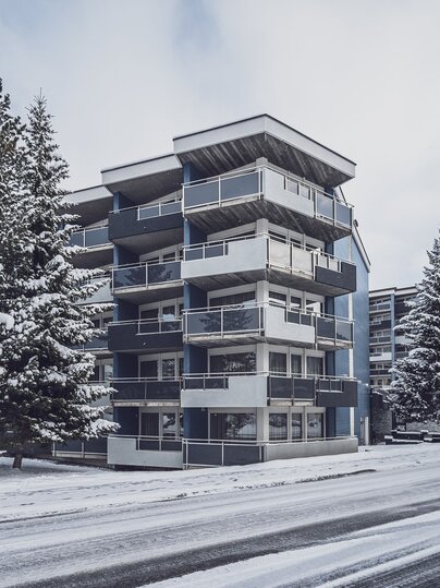 Aussenansicht eines mehrstöckigen Gebäudes mit blauer Fassade und Glasbalkonen | © Davos Klosters Mountains 