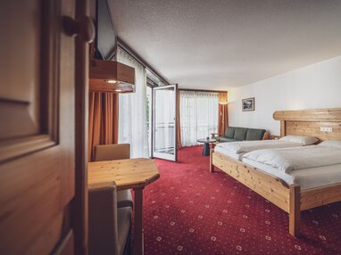 Grosses Zimmer mit Doppelbett, Balkon und rotem Teppich  | © Davos Klosters Mountains 