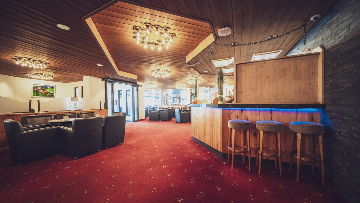 Hotel lobby incl. bar with bar seats, club tables and lounge chairs, red carpeting | © Davos Klosters Mountains Hotel lobby incl. bar with bar seats, club tables and lounge chairs, red carpeting | © Davos Klosters Mountains
