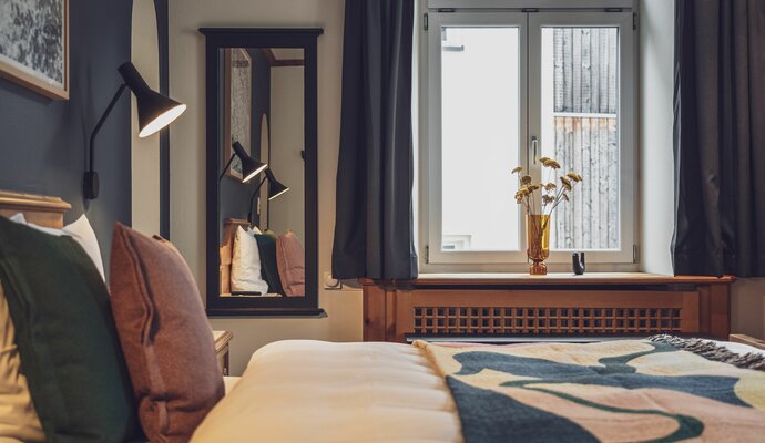 Doppelbettzimmer mit Bettwäsche, Fenster, Spiegel und Nachttischlampe | © Davos Klosters Mountains 