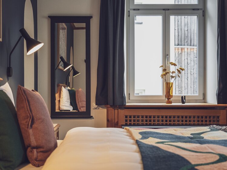 Doppelbettzimmer mit Bettwäsche, Fenster, Spiegel und Nachttischlampe | © Davos Klosters Mountains 
