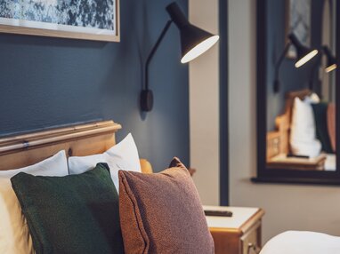 Hotelbett mit Bettlampe und Spiegel im Hintergrund | © Davos Klosters Mountains