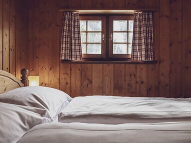 Doppelbett mit kleine Fenster | © Davos Klosters Mountains