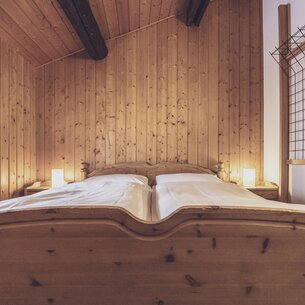Double bed in the bright hotel room with lots of wood | © Davos Klosters Mountains