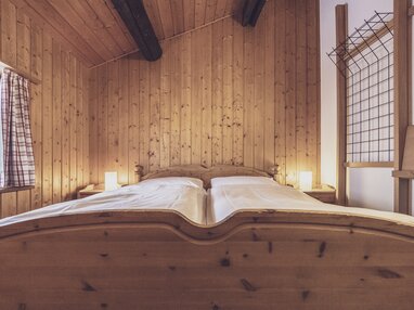 Doppelbett im hellen Hotelzimmer mit viel Holz | © Davos Klosters Mountains