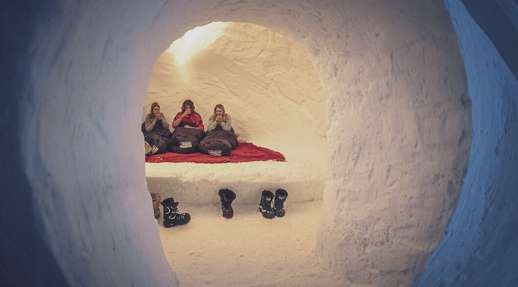 Schnee Iglu mit 3 im Schlafsack sitzenden, Tee trinkenden Personen | © Davos Klosters Mountains Schnee Iglu mit 3 im Schlafsack sitzenden, Tee trinkenden Personen | © Davos Klosters Mountains