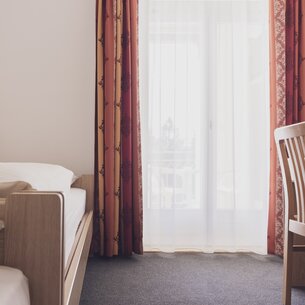 Einzelbett mit Stuhl und Fenster | © Davos Klosters Mountains