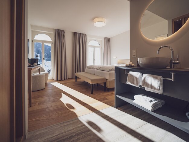 helles Doppelbettzimmer mit Lavabo und Sitzgelegenheit | © Davos Klosters Mountains 
