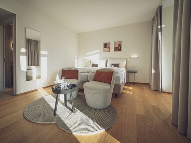 Helles Doppelzimmer mit Holzboden, Salontisch und Sitzgelegenheiten | © Davos Klosters Mountains 