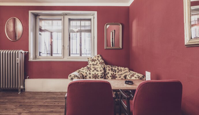 Raum mit rotem Interieur, Tisch und Stühlen | © Davos Klosters Mountains 