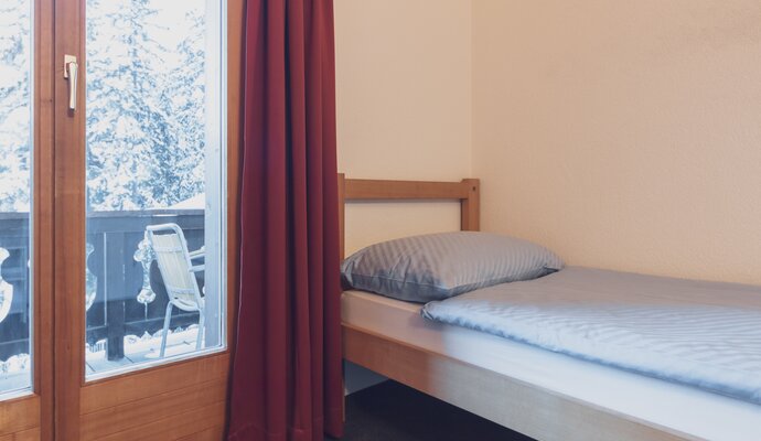 Einzelbett mit Kissen und Bettdecke | © Davos Klosters Mountains