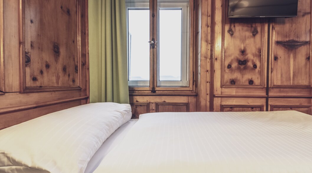 Hotel bed with wood panelling | © Davos Klosters Mountains