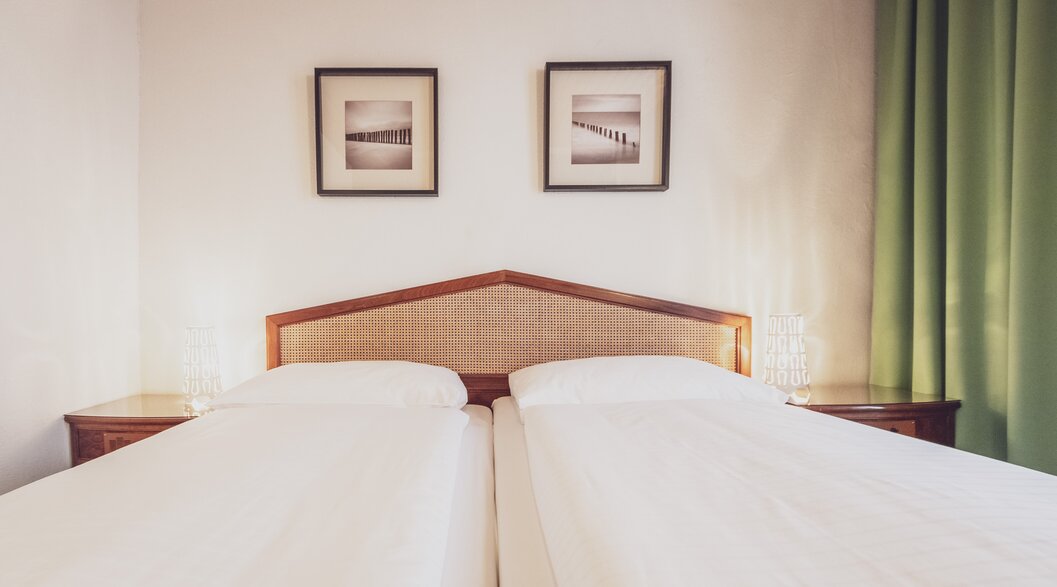 Hotel bed with pictures on the wall | © Davos Klosters Mountains