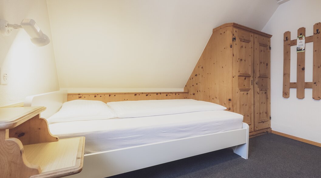 Hotel bed with bedside table | © Davos Klosters Mountains