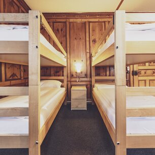 Two bunk beds in a shared room at the Hotel Montana with a beautiful wooden wall. | © Davos Klosters Mountains