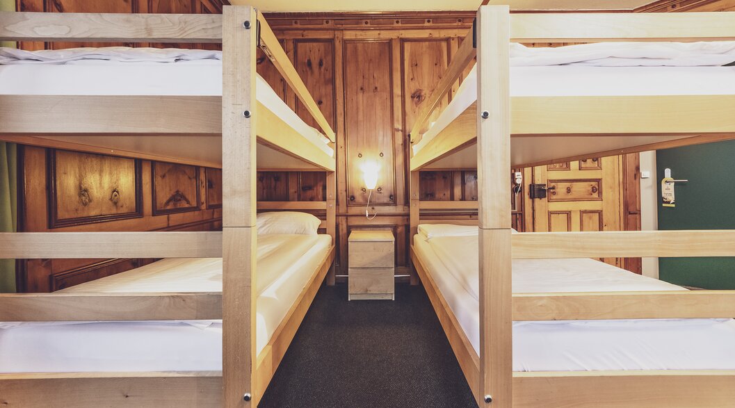 Two bunk beds in a shared room at the Hotel Montana with a beautiful wooden wall. | © Davos Klosters Mountains