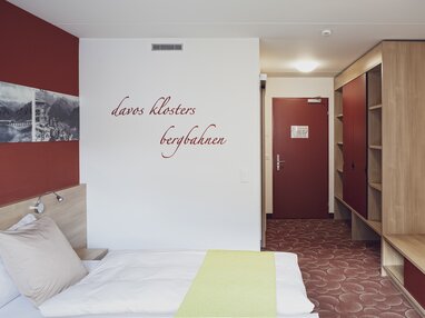 Roter Schriftzug ziert ein Doppelzimmer im Hotel Ochsen 2 passend zu Wände und Teppich.  | © Davos Klosters Mountains
