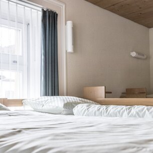 Several simple single beds in a room in the Sporthof. | © Davos Klosters Mountains