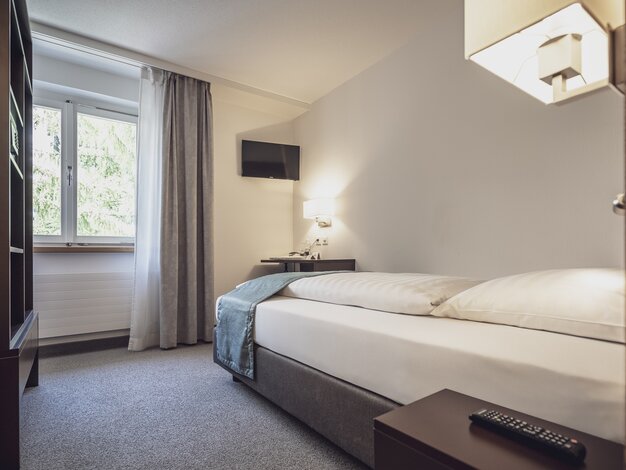 Einzelzimmer mit Bett, Fenster und einem Fernseher | © Davos Klosters Mountains
