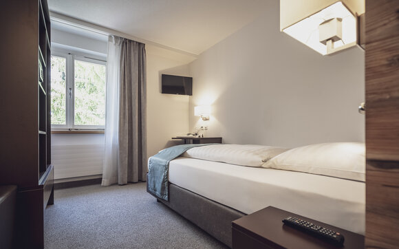 Single room with bed, window and a TV set | © Davos Klosters Mountains