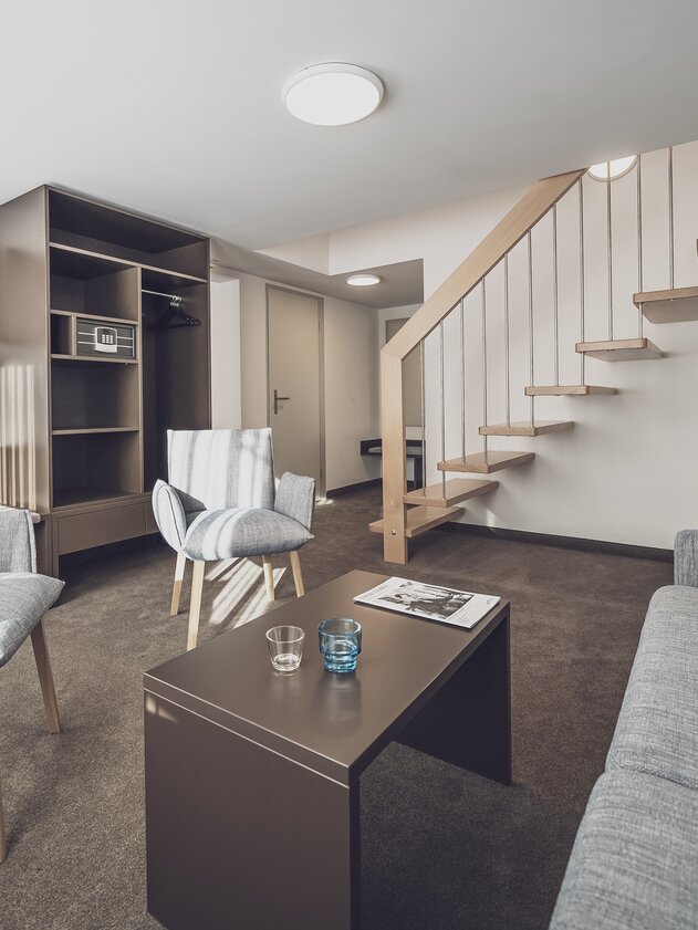Wohnzimmer mit Sofa und Holztreppe nach oben | © Davos Klosters Mountains Wohnzimmer mit Sofa und Holztreppe nach oben | © Davos Klosters Mountains