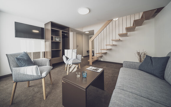 Wohnzimmer mit Sofa und Holztreppe nach oben | © Davos Klosters Mountains