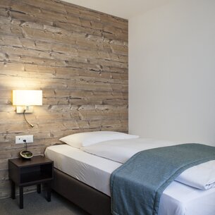 Einzelzimmer mit Bett und Nachttisch | © Davos Klosters Mountains