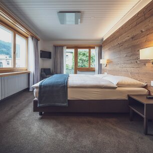 Hotelzimmer mit Doppelbett und grossen Fenstern mit Aussicht | © Davos Klosters Mountains