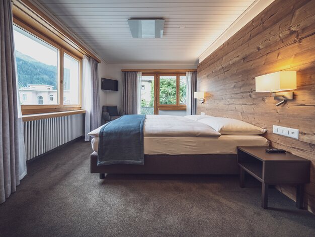 Hotelzimmer mit Doppelbett und grossen Fenstern mit Aussicht | © Davos Klosters Mountains