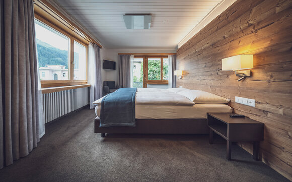 Hotel room with double bed and large windows with view | © Davos Klosters Mountains