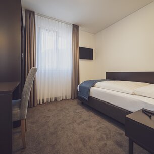 Moderns Einzelzimmer Comfort im Hotel Strela in warmen braun Tönen. | © Davos Klosters Mountains