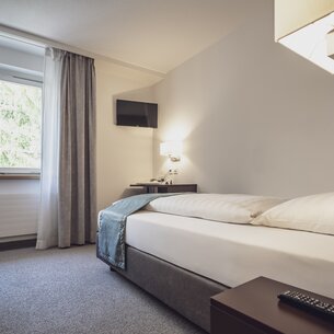 Einzelzimmer mit Bett, Fenster und einem Fernseher | © Davos Klosters Mountains