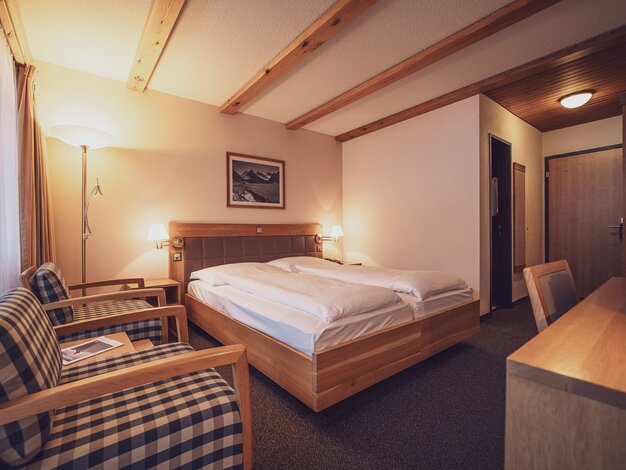 Doppelbettzimmer mit Couchsessel und Schreibtisch | © Davos Klosters Mountains 