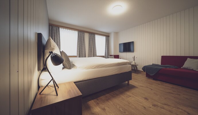 Schlafzimmer mit Doppelbett und roter Couch | © Davos Klostes Mountains
