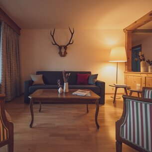 Wohnzimmer mit Sessel, Couch und Geweih an der Wand | © Davos Klosters Mountains