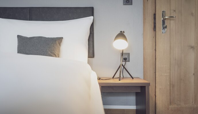Schlafzimmer mit Bett und Nachttischlampe | © Davos Klosters Mountains