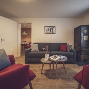 Wohnzimmer mit Sessel, Couch und Ofen | © Davos Klosters Mountains