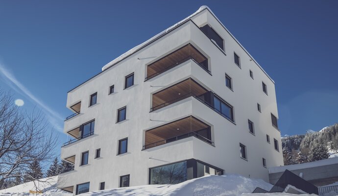 Fünf Stöckiges Ferienwohnungs Haus im Schnee mit blauem Himmel | © Davos Klosters Mountains