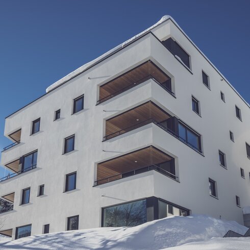 Fünf Stöckiges Ferienwohnungs Haus im Schnee mit blauem Himmel | © Davos Klosters Mountains