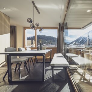Grosser Esstisch mit grosser Glasfront und viel Aussicht auf die Berge | © Davos Klosters Mountains