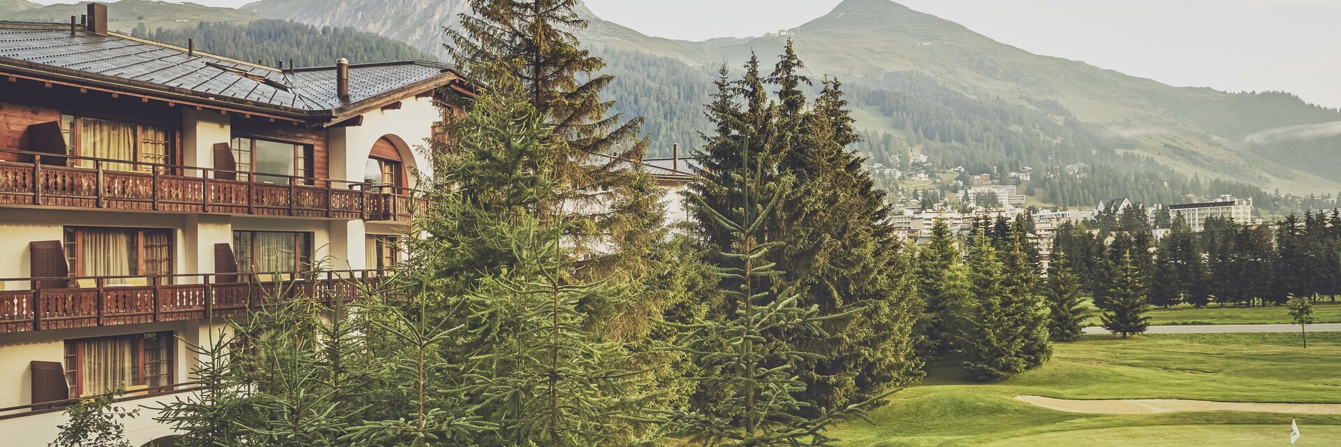Mehrstöckiges Gebäude mit Balkonen umringt von Nadelbäumen  | © Davos Klosters Mountains 