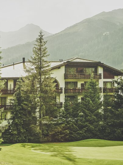 Mehrstöckiges Gebäude mit Balkonen umringt von Nadelbäumen  | © Davos Klosters Mountains 