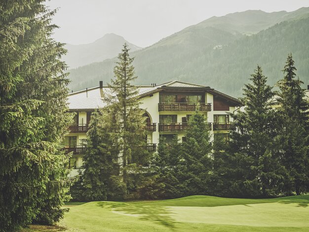 Mehrstöckiges Gebäude mit Balkonen umringt von Nadelbäumen  | © Davos Klosters Mountains 