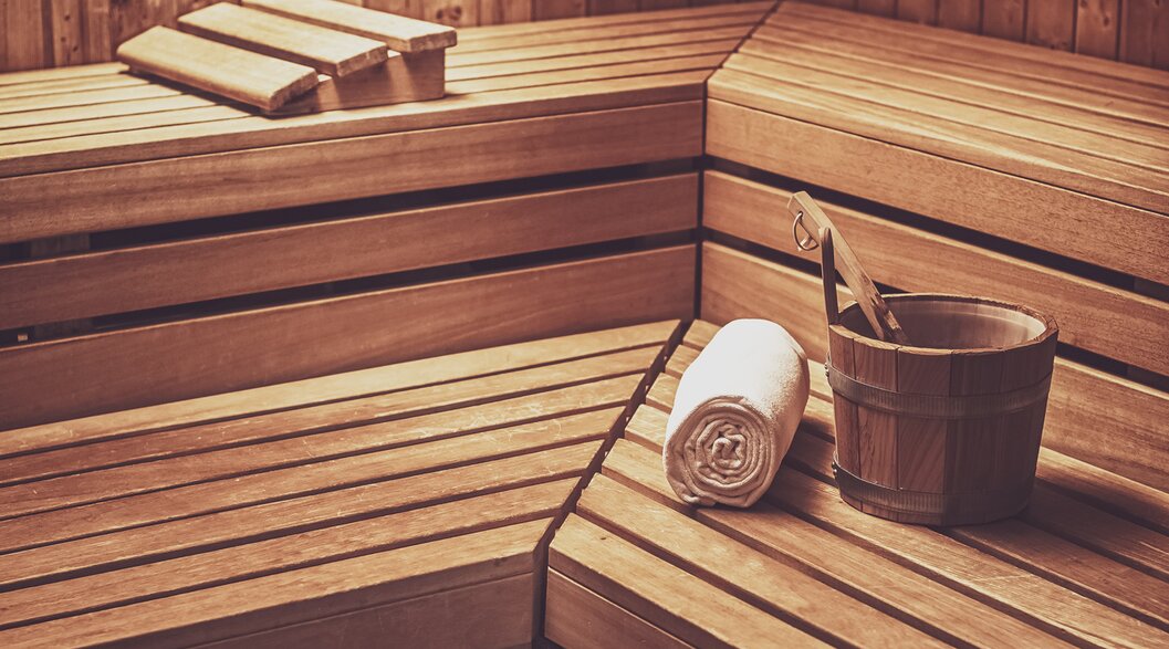 Finnische Sauna aus Holz mit einem Aufgusseimer, Kelle und einem Saunatuch auf der Liegefläche. | © Davos Klosters Mountains