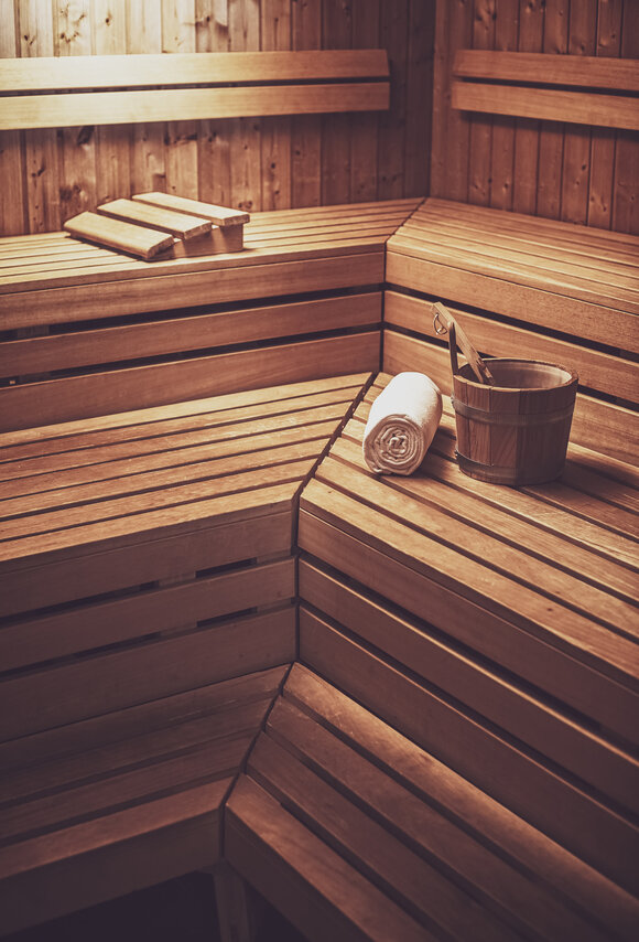 Finnische Sauna aus Holz mit einem Aufgusseimer, Kelle und einem Saunatuch auf der Liegefläche. | © Davos Klosters Mountains